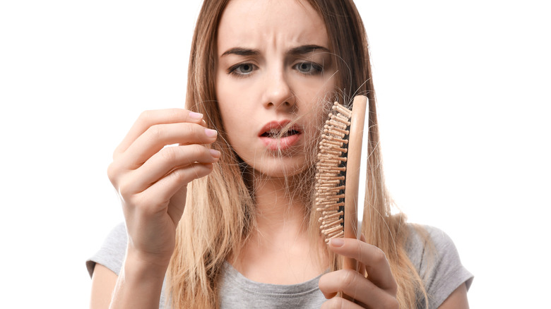 concerned woman staring at hair in her brush