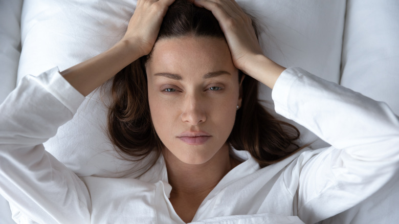 dazed woman looking up from bed    