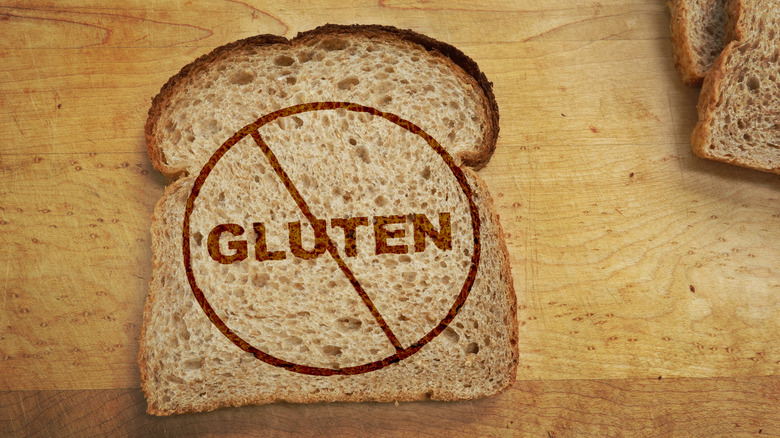 a slice of bread that has on it the word gluten circled with a line through it against a wooden surface