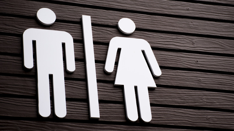 close up of a restroom sign against a dark brown wooden wall