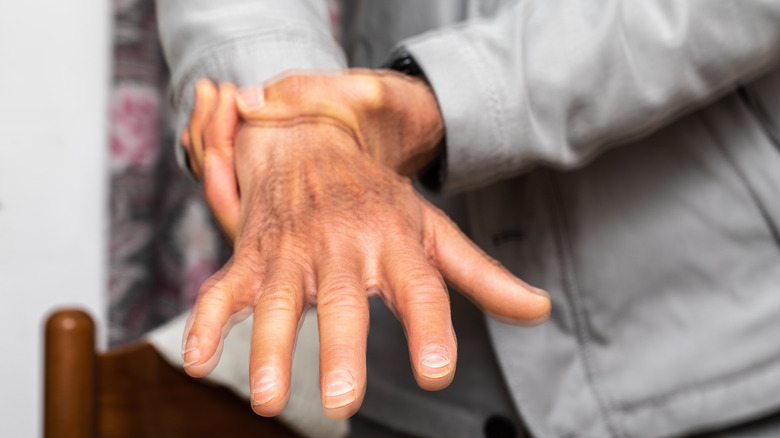 close up of a man holding his shaking hand by the wrist