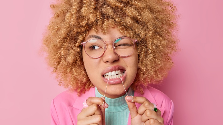 Woman holds floss in teeth