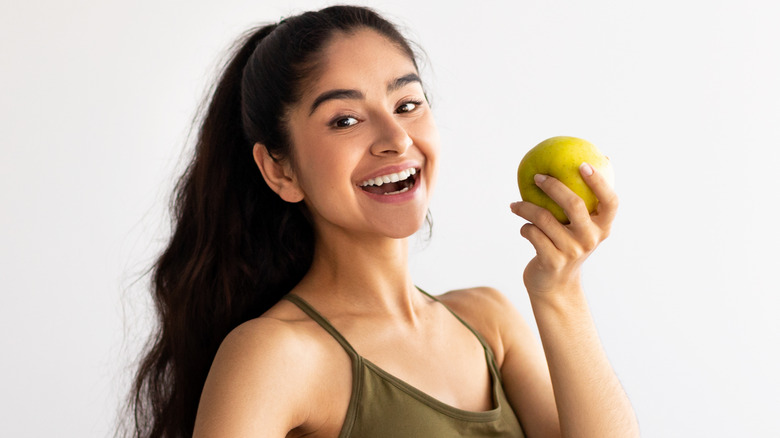 Smiling woman holding green apple