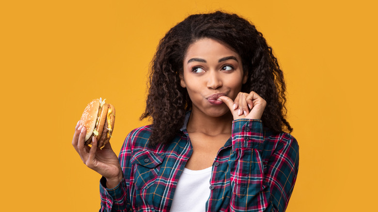 woman eating burger with yellow background