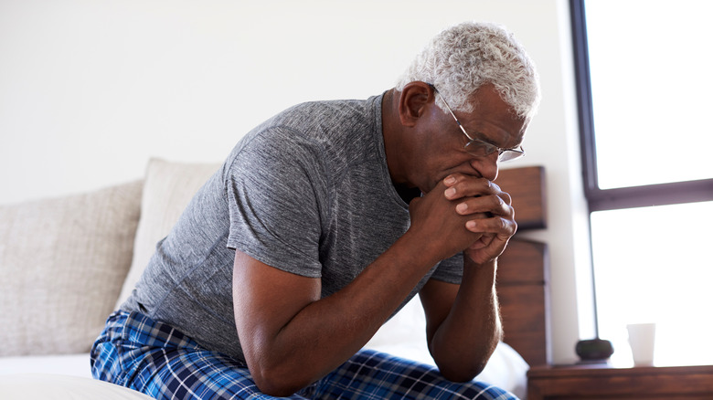 worried man sitting on bed's edge