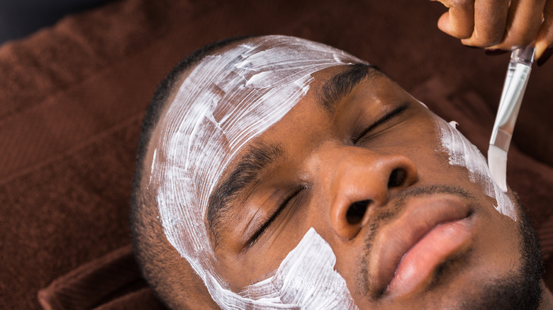 young man relaxing at spa face mask