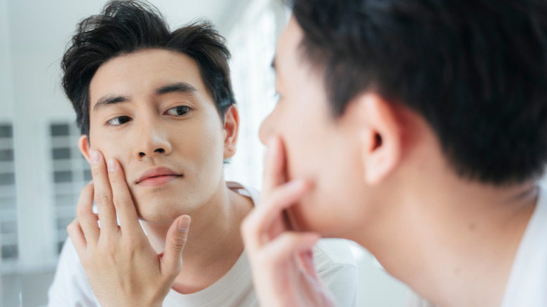 Young asian man looking in the mirror