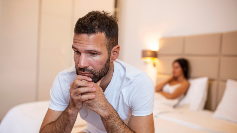 frustrated man sitting on edge of bed