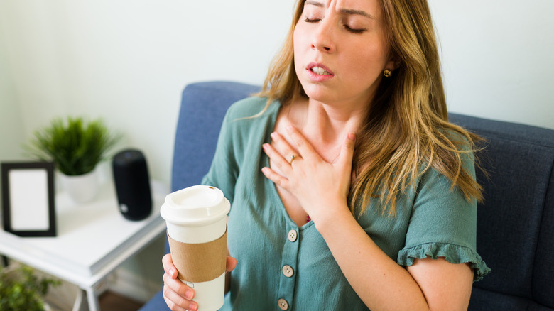 woman drinking coffee touching chest