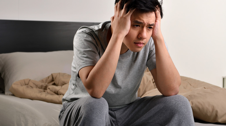 man with insomnia sitting on bed