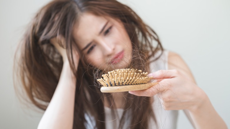 woman staring at hairbrush with hair