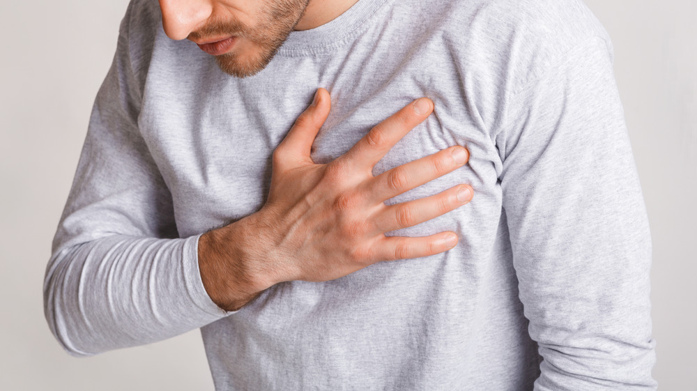 young man in gray holding chest ache