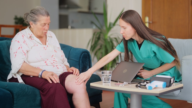 doctor looking at older woman's leg