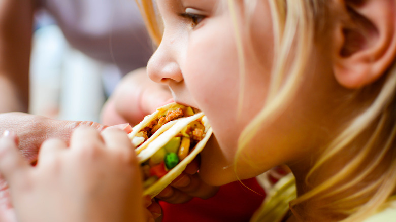 child eating chicken taco