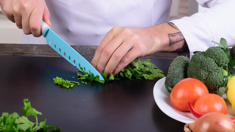 close up of chef's hands chopping fresh cilantro