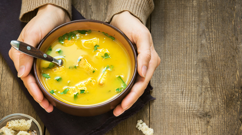 hands cradling bowl of soup