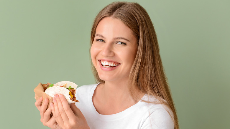 smiling woman eating a soft taco