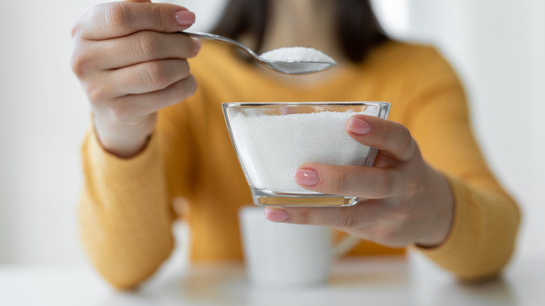 Woman adding sugar to her coffee