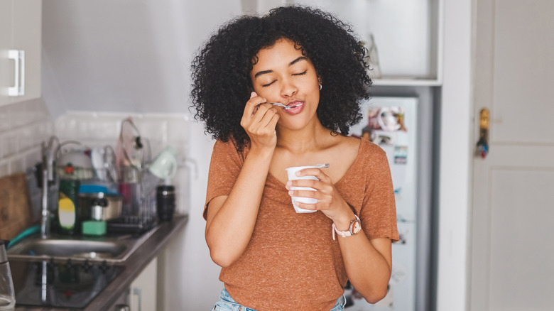 woman eating yogurt in her kitchen