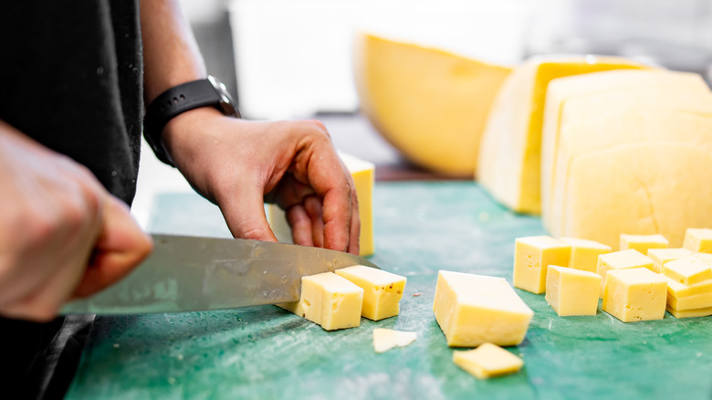 slicing cheddar cheese on cutting board