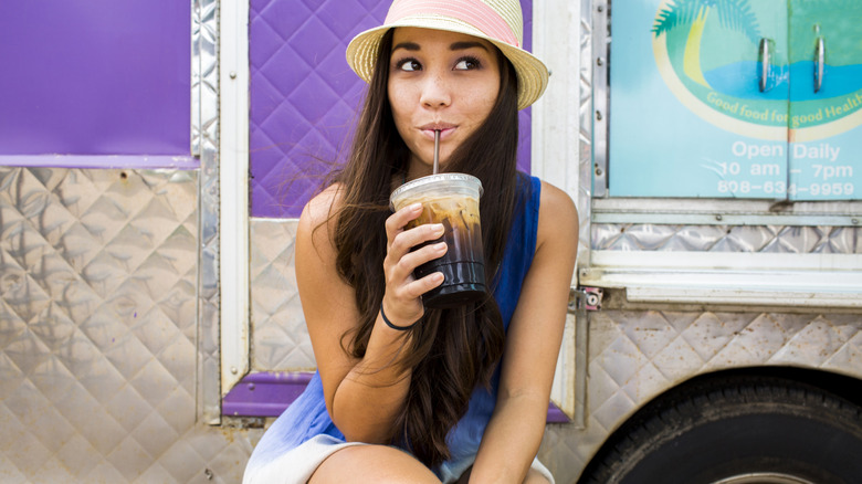 A young woman drinking iced coffee drink through a straw