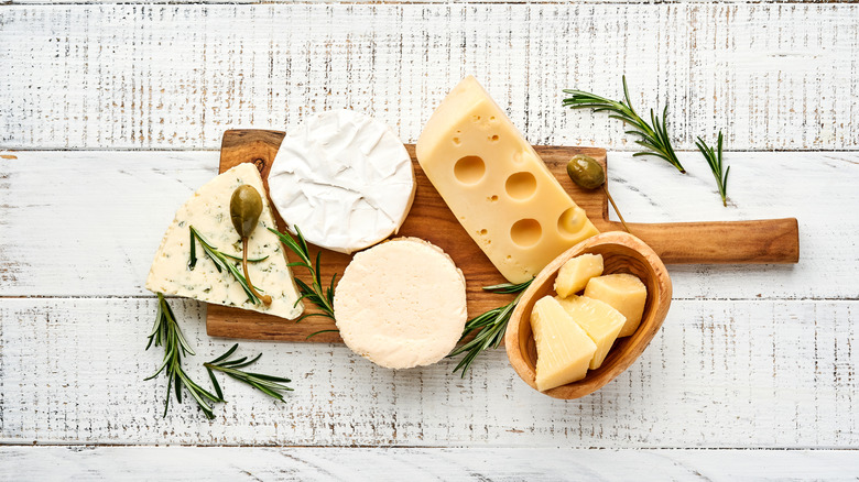 an assortment of cheese laid out on a cheese board