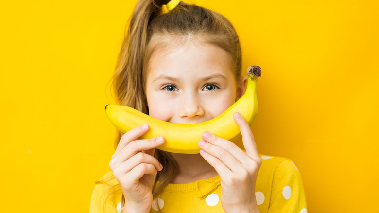 girl holding banana as smile