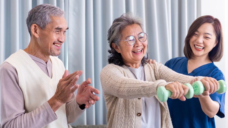 Helping a senior woman lift weights