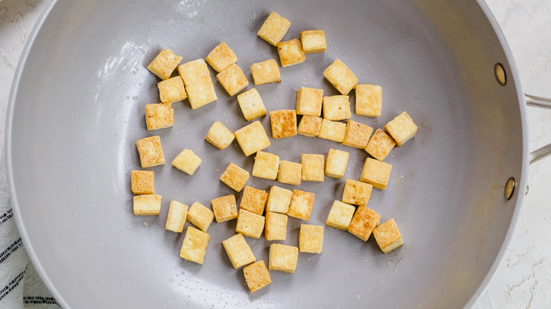 Golden tofu cubes in skillet