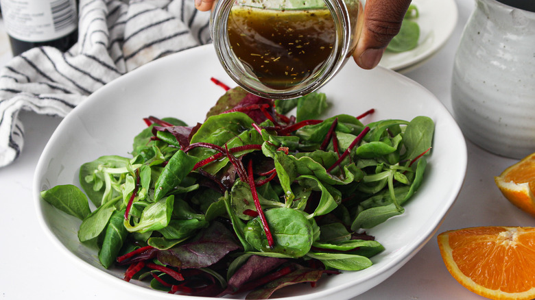 pouring salad dressing on greens