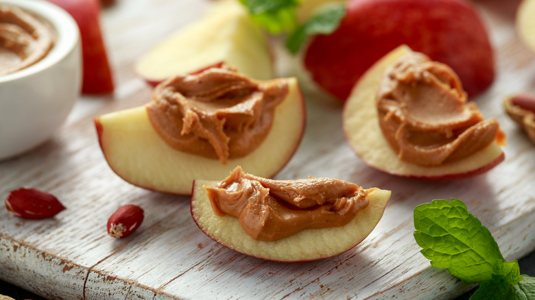 apples with peanut butter on wooden board