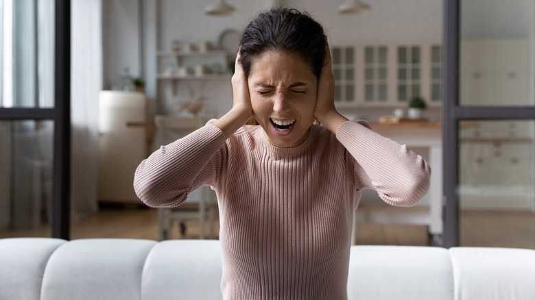 woman covering ears experiencing loud noise