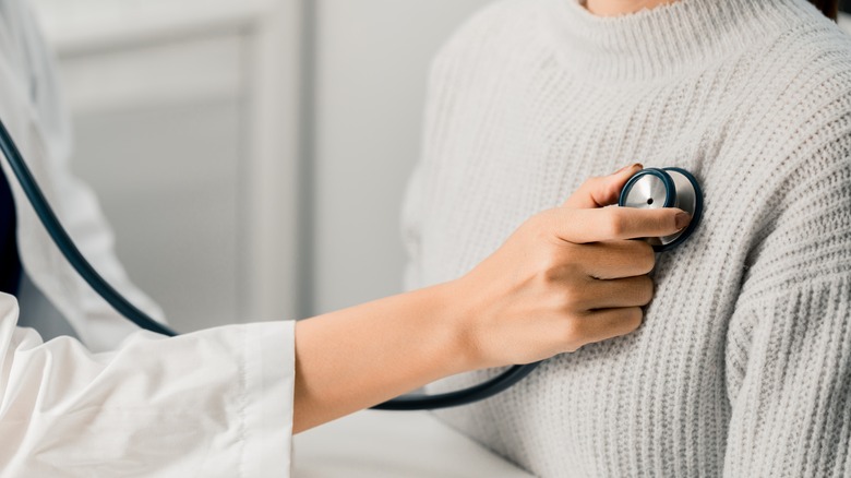 Cardiologist listening to woman's heart with stethoscope