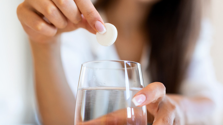 woman dropping medication into water 