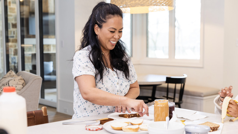 Smiling woman making peanut butter and jelly sandwich