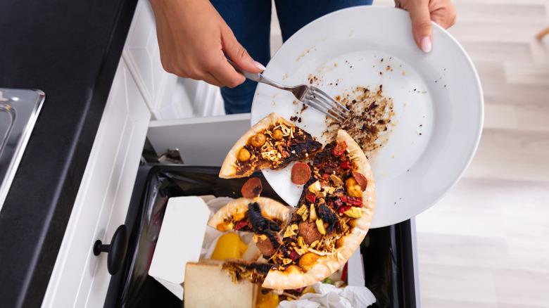 person throwing pizza slices into garbage