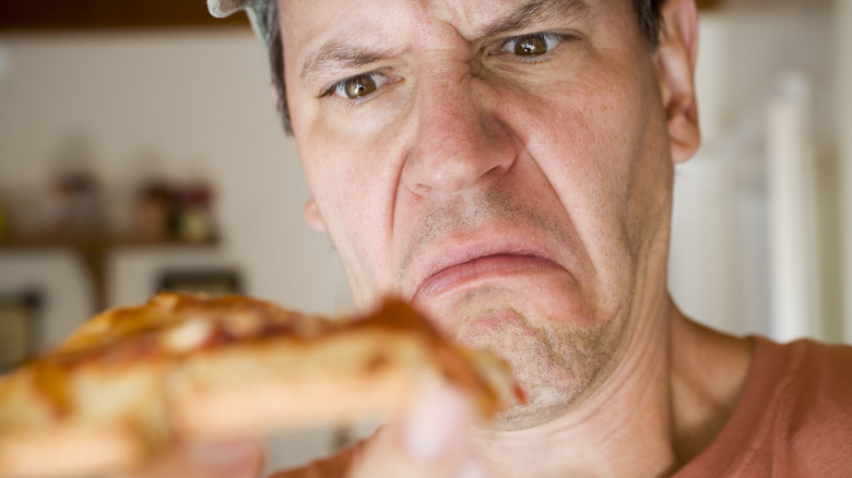 disgusted man looking at pizza