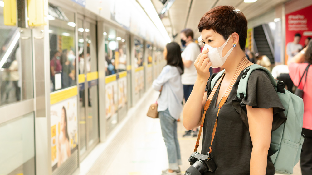 woman wearing a mask waiting to board a train 