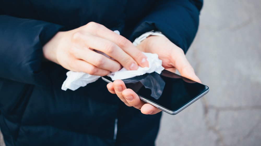 woman cleans smartphone with cloth