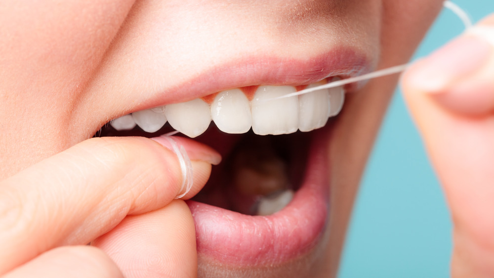 Close up of woman flossing her teeth