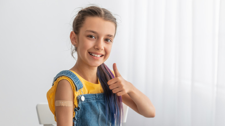 Girl smiling and giving thumbs up with bandage on arm