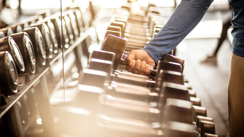 A hand reaching for weights on a rack