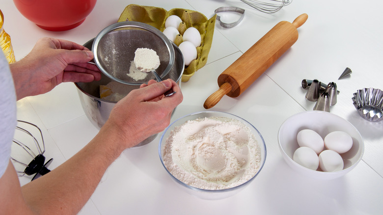 Close up of woman's hands sifting flour