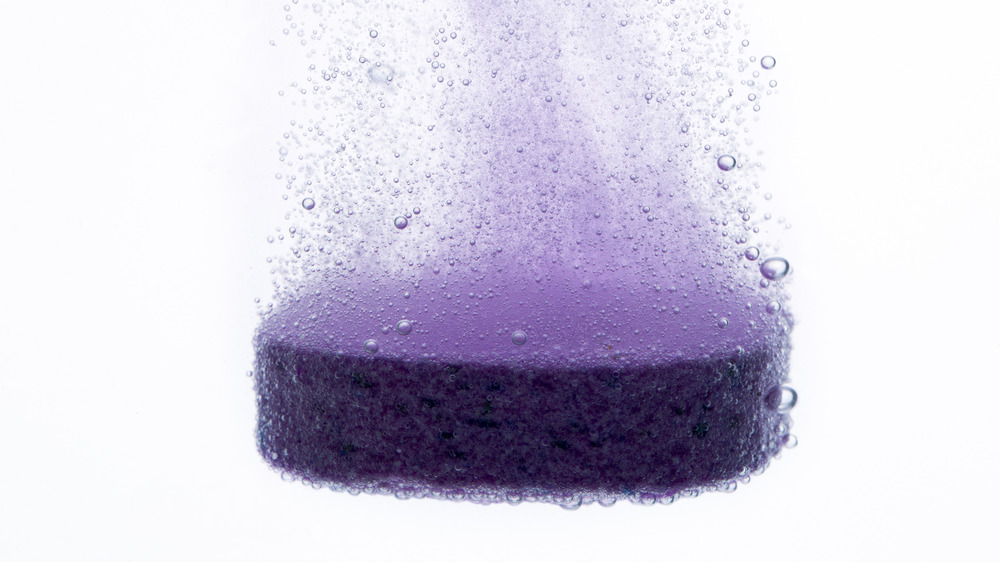 a purple antacid pill dissolving in water 