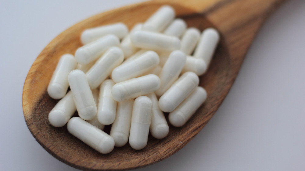 Inositol capsules on wooden spoon