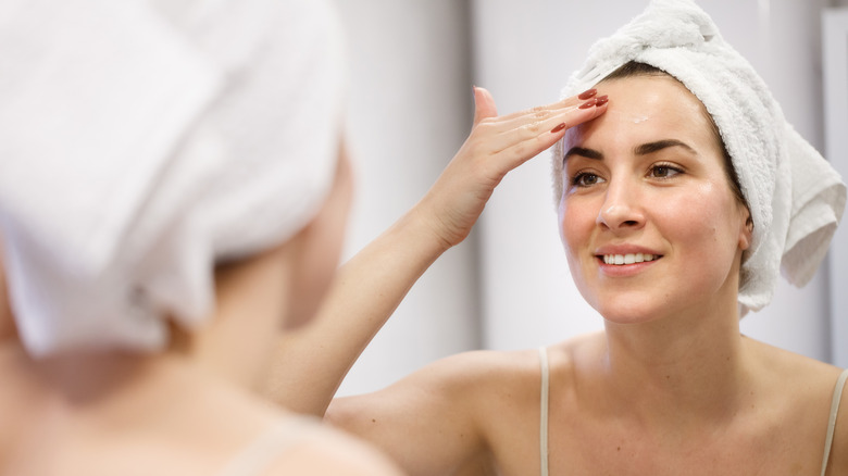 Smiling woman applying lotion to forehead