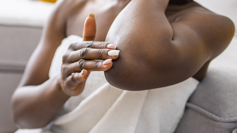 Hand rubbing lotion on elbow