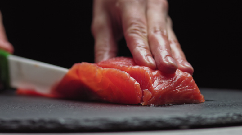Sushi chef slicing fresh salmon
