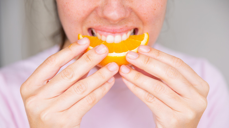 Mouth biting into orange slice