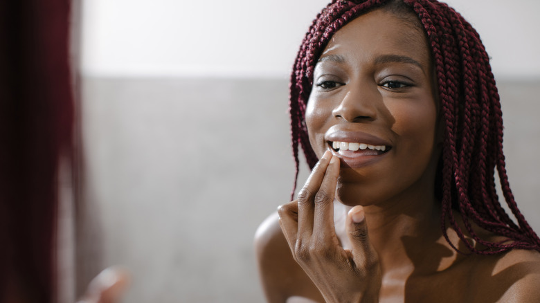 Smiling woman applying lip balm